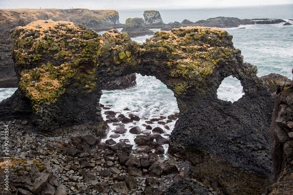 Rock formation of lava with hole and sea