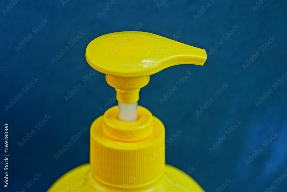 yellow plastic dispenser on the bottle on a blue background yellow plastic dispenser on the bottle on a blue background