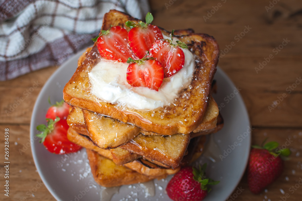 Close-up of french toast with fresh strawberries, coconut shreds and honey, on wooden background Close-up of french toast with fresh strawberries, coconut shreds and honey, on wooden background