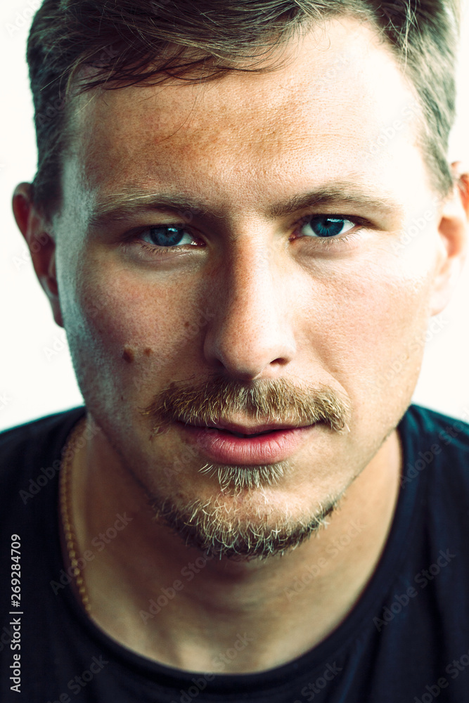 Fototapeta premium Colored closeup portrait of caucasian man with blue eyes, mustache, little beard and gold chain in black t-shirt 