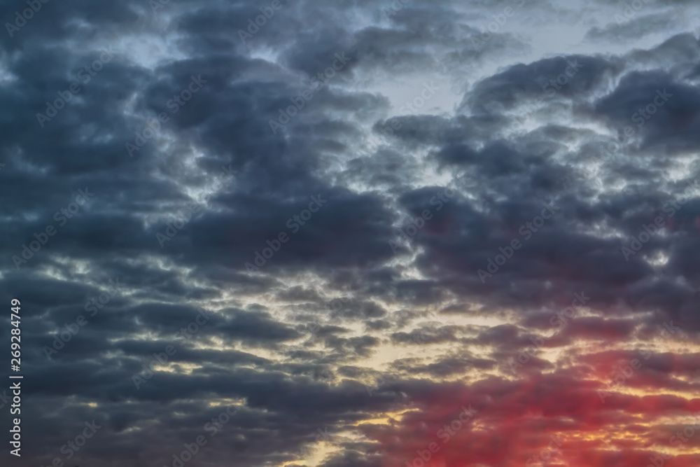 Obraz premium The sky with dark clouds illuminated by the setting sun
