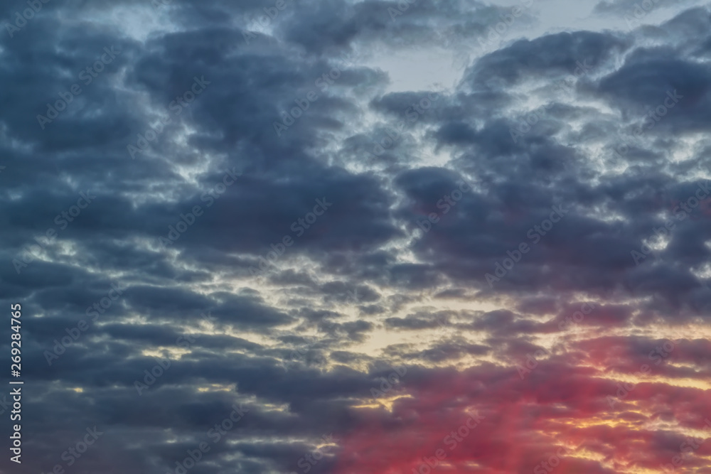 Obraz premium The sky with dark clouds illuminated by the setting sun