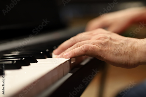 hands playing piano, one hand, musician playing the piano close-up on the hand, small depth of field on keys