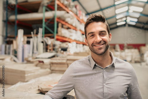 Young manager smiling while standing in a large warehouse