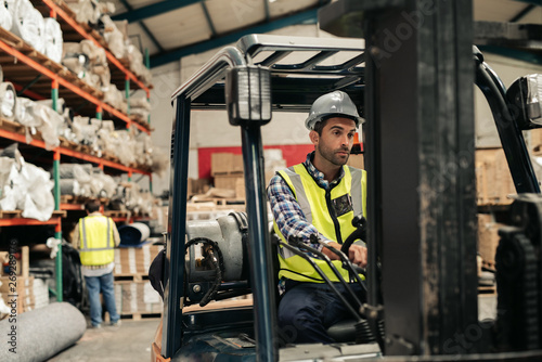 Forklift driver moving stock on the floor of a warehouse