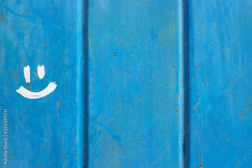 Old blue painted corrugated metal fence with stains, scratches, traces of dirt and rust and drawn smile. Old blue painted corrugated metal fence with stains, scratches, traces of dirt and rust and drawn smile.