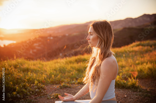 Female athlete with eyes closed meditating on mountain during sunset