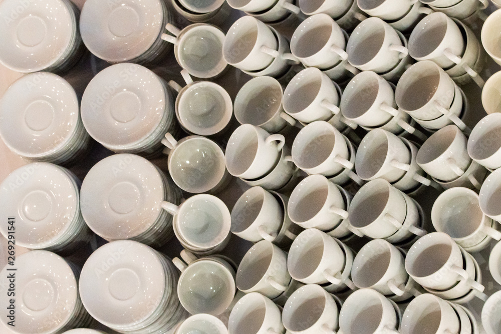 White coffee cups in rows on table. Cup prepared for hot drink such as coffee or tea in local coffee cafe or restaurant White coffee cups in rows on table. Cup prepared for hot drink such as coffee or tea in local coffee cafe or restaurant