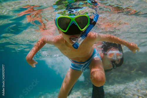 Obraz na plátně Child learning to snorkel with his mother in sea
