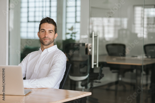 Confident young businessman sitting at his office desk
