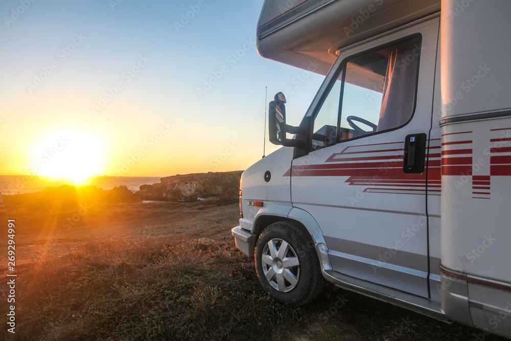 Old van or camp truck stands on ocean or sea coast on beautiful sunset of sunrise