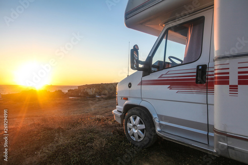 Old van or camp truck stands on ocean or sea coast on beautiful sunset of sunrise