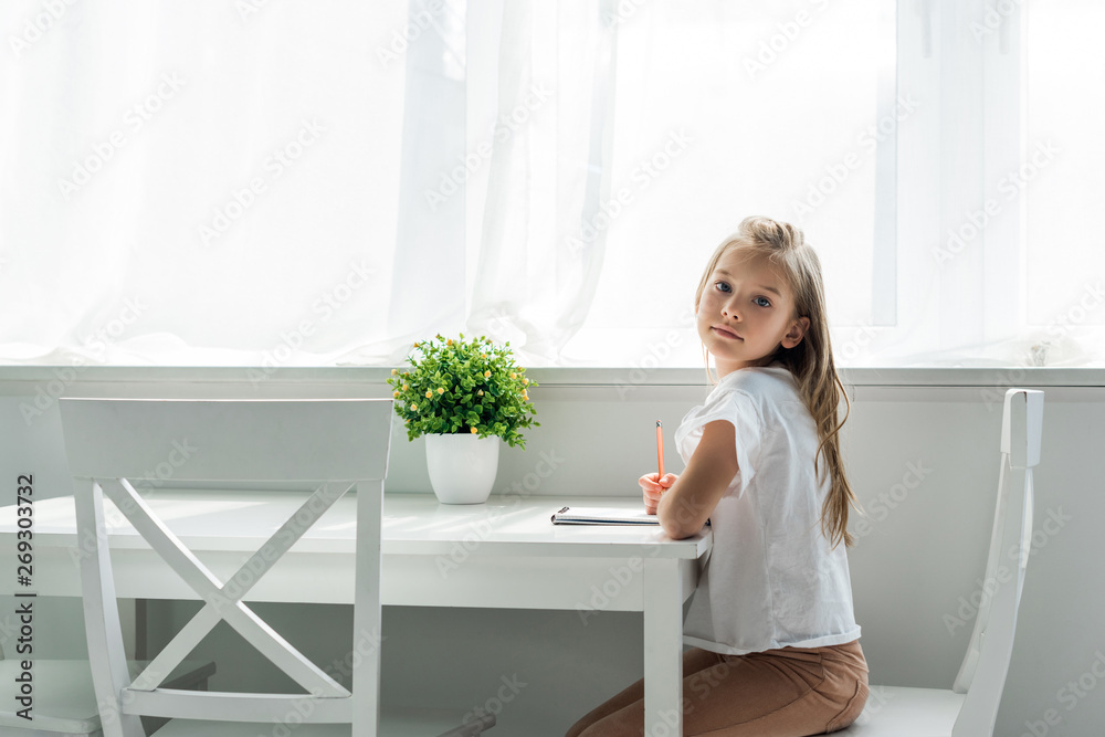 cute kid sitting and holding pencil near notebook at home cute kid sitting and holding pencil near notebook at home