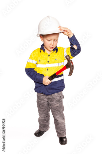 Young blond caucasian boy role playing as a construction worker in a yellow and blue hi-viz shirt, boots, white hard hat, a red hammer without tape measure. © EdwardsMediaOnline