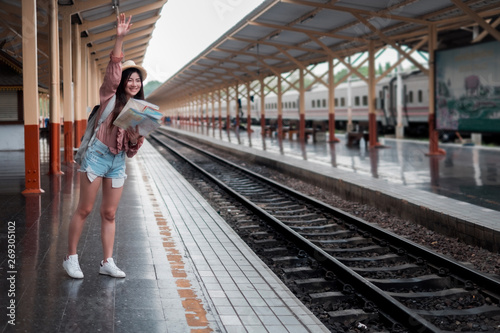 Smiling woman traveler with backpack holding world map planning vacation on holiday relaxation at the train station,relaxation concept, travel concept