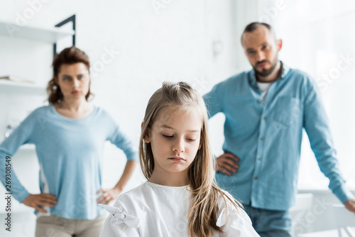 selective focus of upset child near sad parents standing at home © LIGHTFIELD STUDIOS