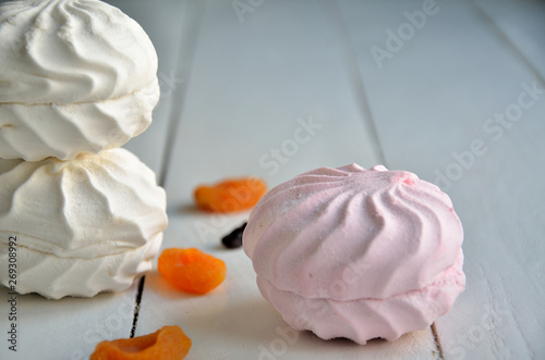 White, pink marshmallow, raisins, dried apricots on a white wooden background.