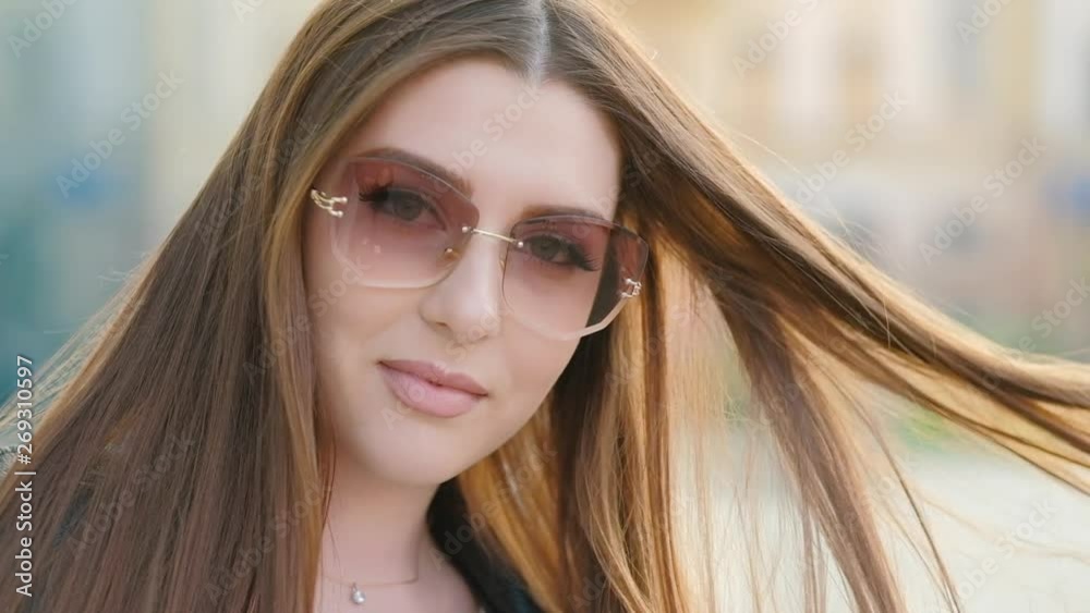 Alluring woman flirting. Gorgeous brunette lady in sunglasses playing with her beautiful long hair at sunset. Blur background. Alluring woman flirting. Gorgeous brunette lady in sunglasses playing with her beautiful long hair at sunset. Blur background.