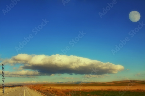 sunset over a field and road under full moon