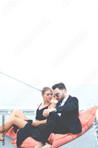 luxury business travelers sit on bean bag and showing their love for each other on a sailing boat. Concept business travel