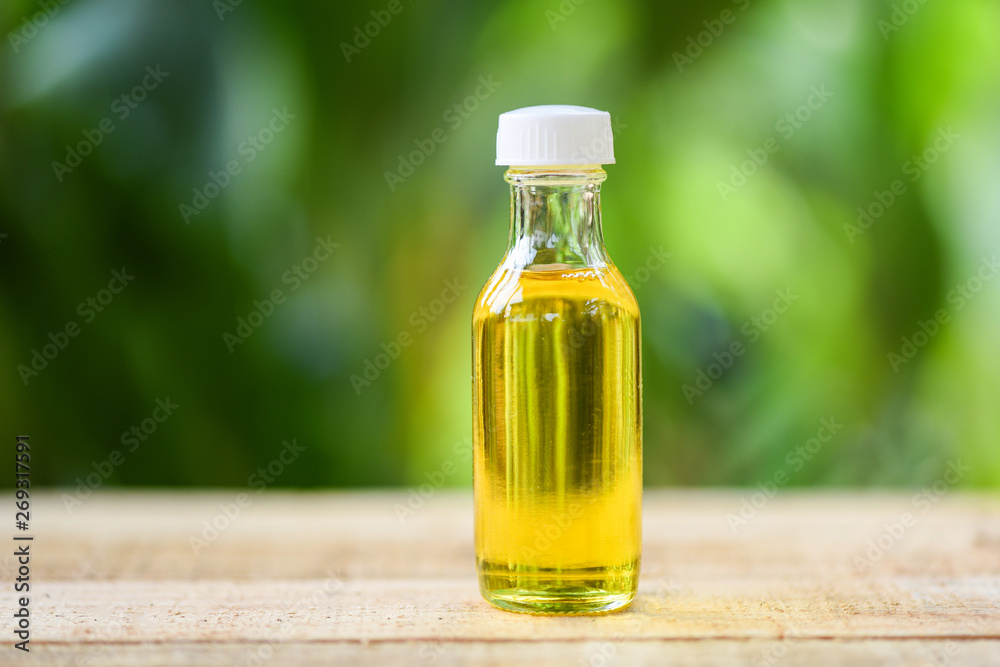 Sesame oil in glass bottles on wooden and nature green Sesame oil in glass bottles on wooden and nature green