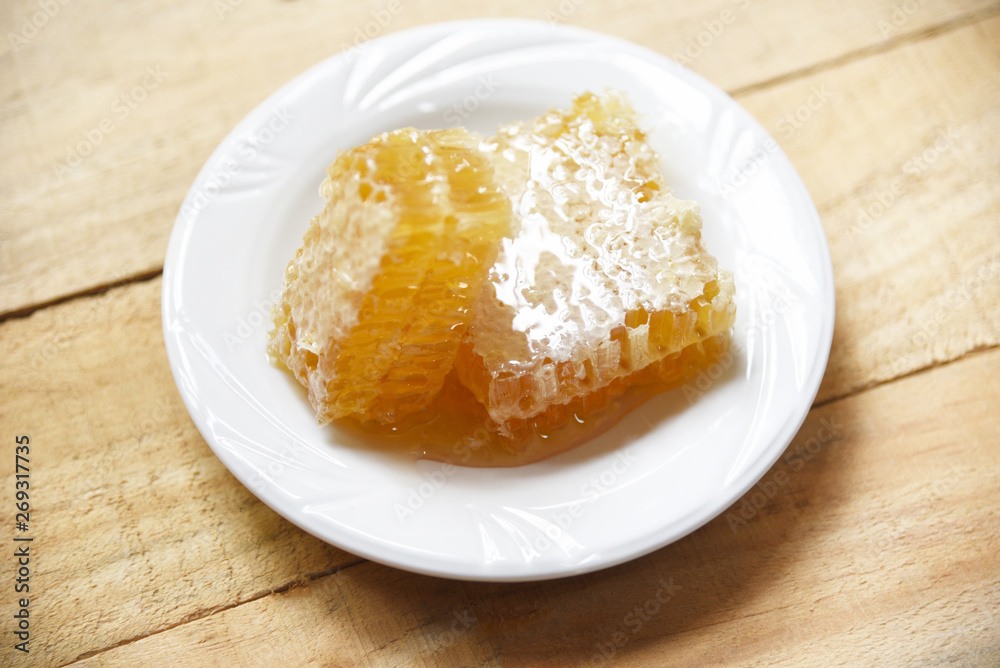 Fresh honey - Close up of yellow sweet honeycomb slice on white plate natural healthy food Fresh honey - Close up of yellow sweet honeycomb slice on white plate natural healthy food