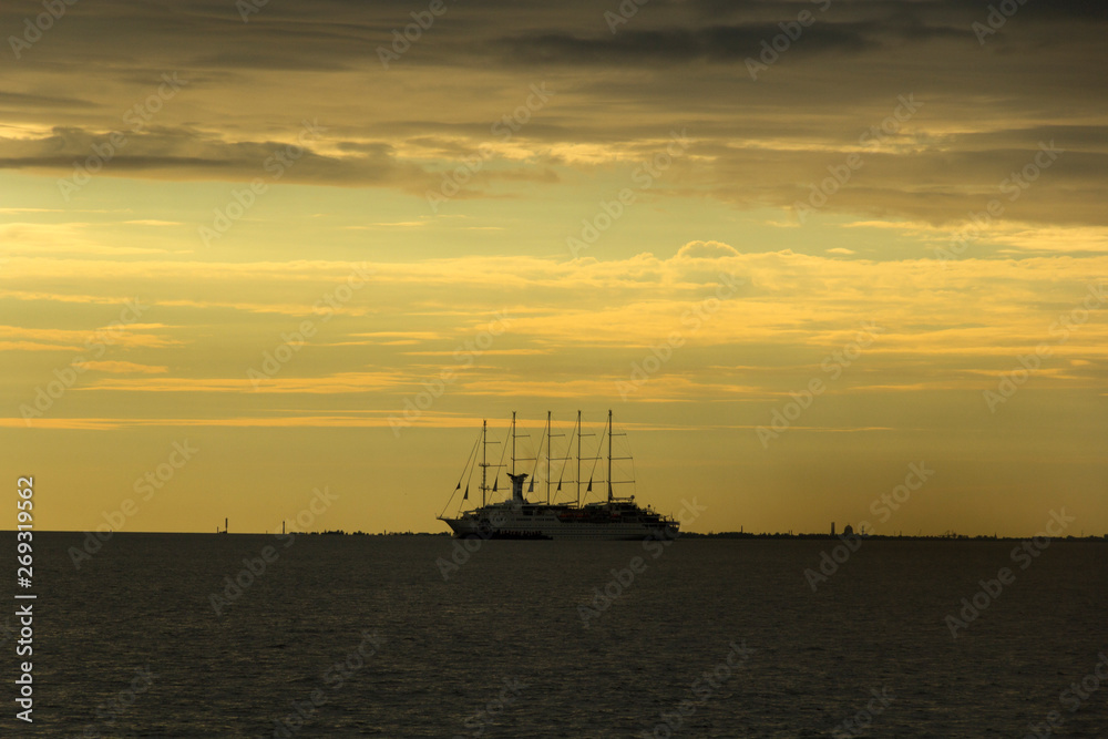 Cruise yacht in the Gulf of Finland on a background of golden sky with clouds