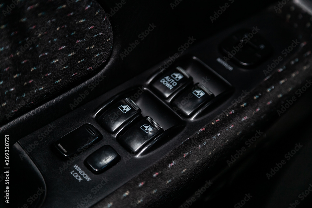 Сlose-up of the car  black interior:  the side door buttons: window adjustment buttons, door lock and other buttons.