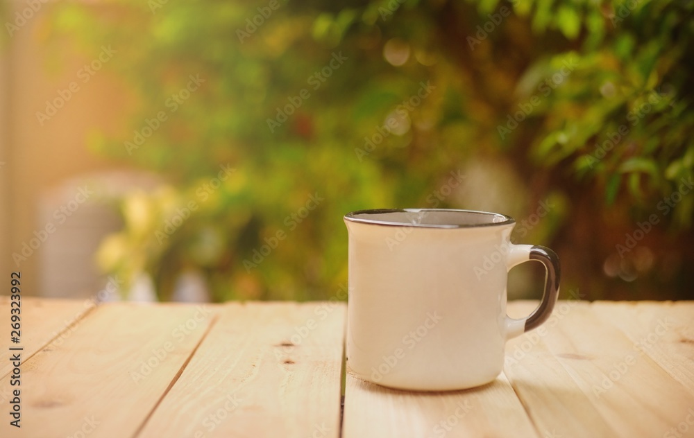 Cup of hot coffee on wooden table in the green garden this morning. Cup of hot coffee on wooden table in the green garden this morning.