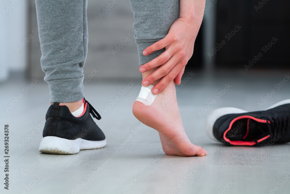 Woman's heel with white medical adhesive bandage from calluses during