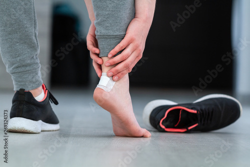 Woman's heel with white medical adhesive bandage from calluses during wearing a new shoe. Skin care feet and prevention of calluses and corns