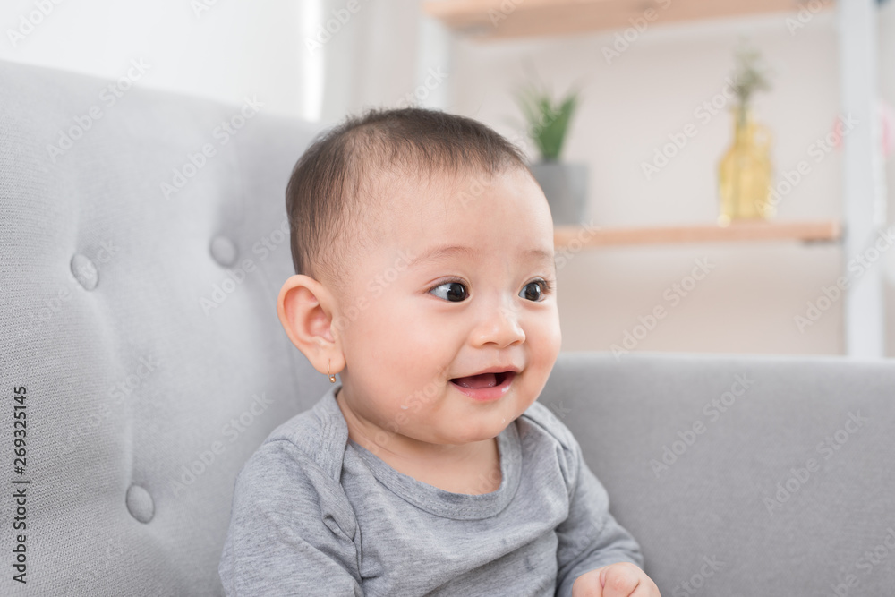 childhood, babyhood and people concept - happy little baby girl sitting on sofa at home childhood, babyhood and people concept - happy little baby girl sitting on sofa at home