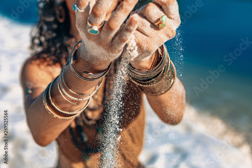 beautiful young woman holding sand in her hands on the beach