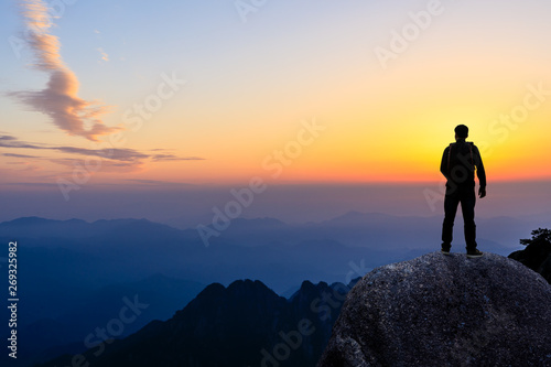 Young happy backpacker on top of a mountain enjoying valley view