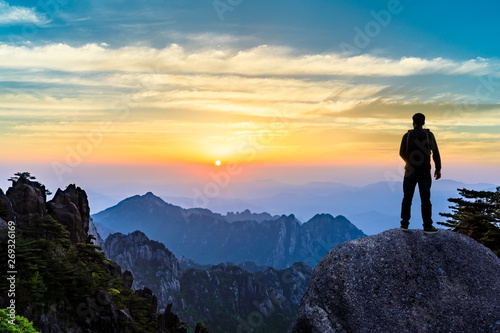 Young happy backpacker on top of a mountain enjoying valley view