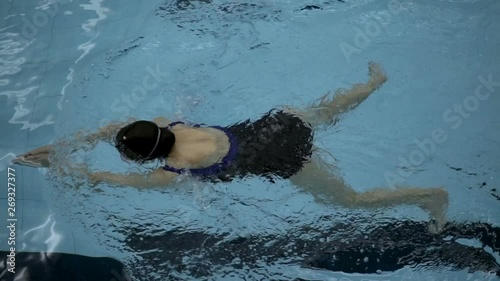 Top view of a female doing breaststroke in swimming pool, steadycam shot