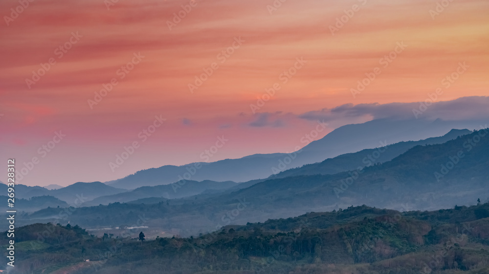 Beautiful nature landscape of mountain range with sunset sky and clouds. Rural village in mountain valley in Thailand. Scenery of mountain layer at dusk. Tropical forest. Natural background.