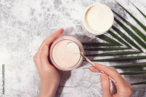 Woman hands  collagen powder and smoothie.