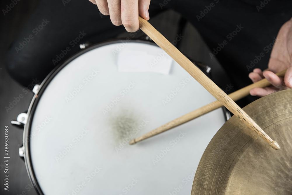 Professional drum set closeup. Man drummer with drumsticks playing drums and cymbals, on black wooden background Professional drum set closeup. Man drummer with drumsticks playing drums and cymbals, on black wooden background