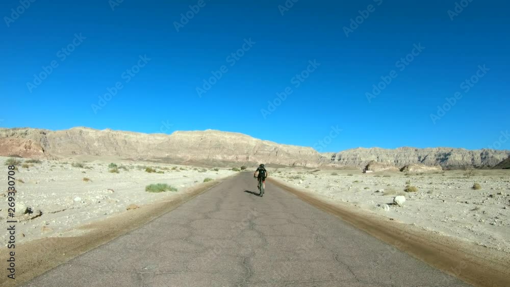 Cyclist riding on an empty Single Desert road, Follow footage.