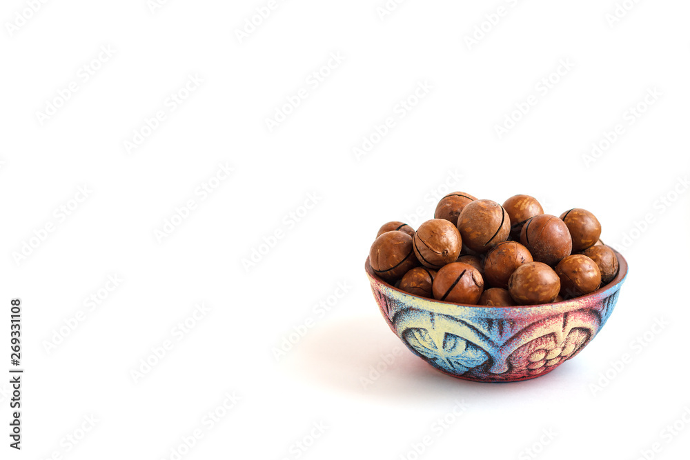 clay bowl with macadamia nuts in shell on white background, copy space clay bowl with macadamia nuts in shell on white background, copy space