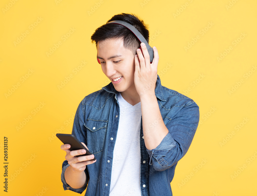 Young smiling man holding headphones and cell phone Young smiling man holding headphones and cell phone