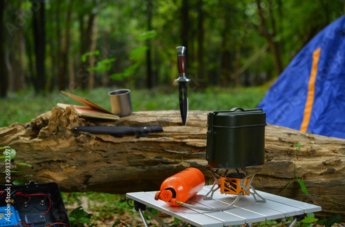 White gas camping stove and pot in the forest. Travel, tourism and camping equipment. Picnic rest, cooking on the nature. Gas stove.