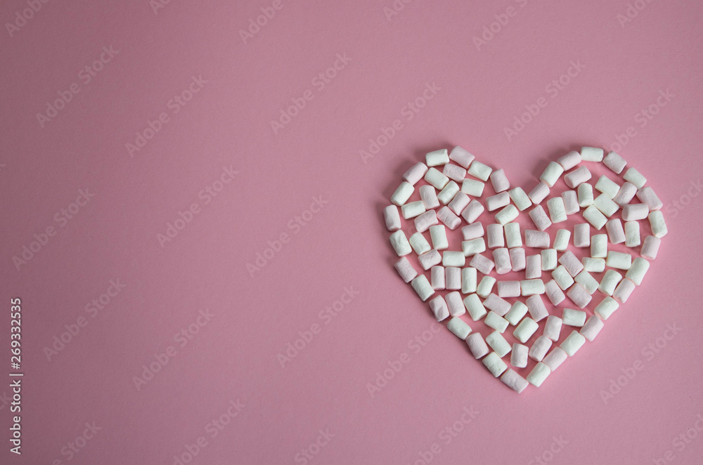 heart laid out of white and pink mini marshmallows on a pink background