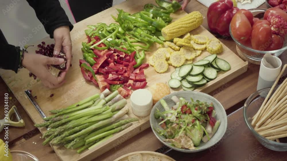 Women preparing vegetable salad together. Cropped shot of young women slicing vegetables and preparing healthy food in kitchen. Organic food concept Women preparing vegetable salad together. Cropped shot of young women slicing vegetables and preparing healthy food in kitchen. Organic food concept
