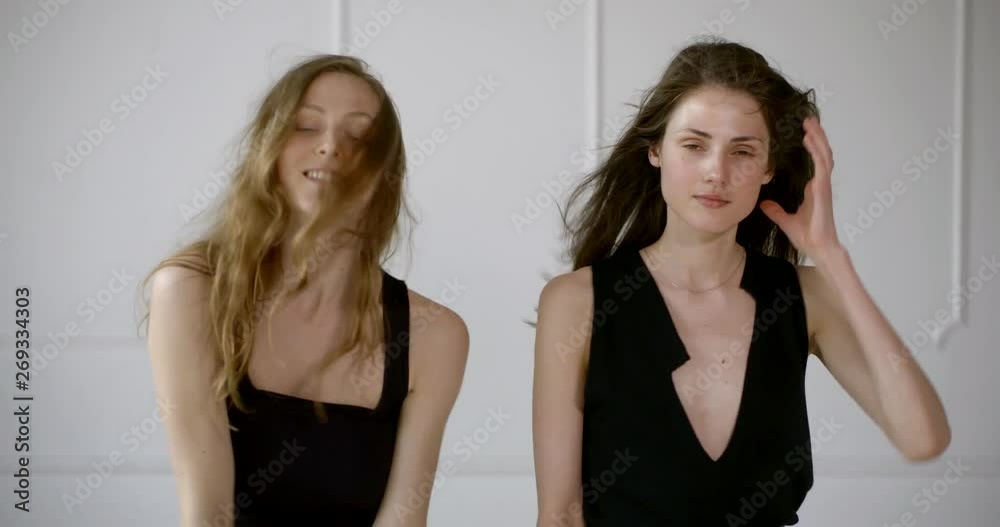 Two cheerful girls in black top posing close to each other on white background Two cheerful girls in black top posing close to each other on white background