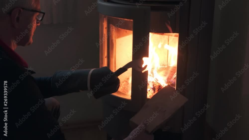 Man putting a log into fire of a wood stove