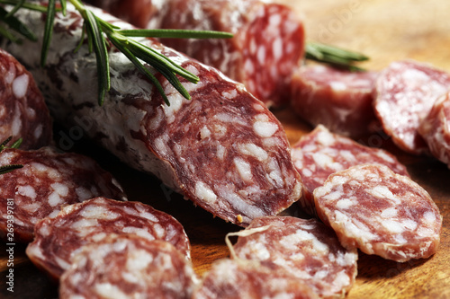 thinly sliced salami sausages on a wooden texture on the background.