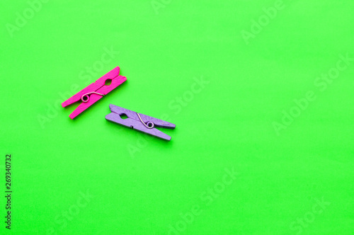 two small colorful wooden clothespin on a green background