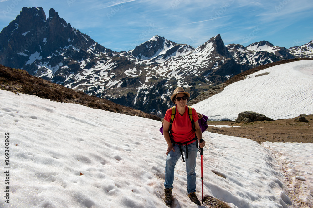 hiker woman walking in the snow, in french Pyrenees mountains, Pic du midi d Ossau in background
